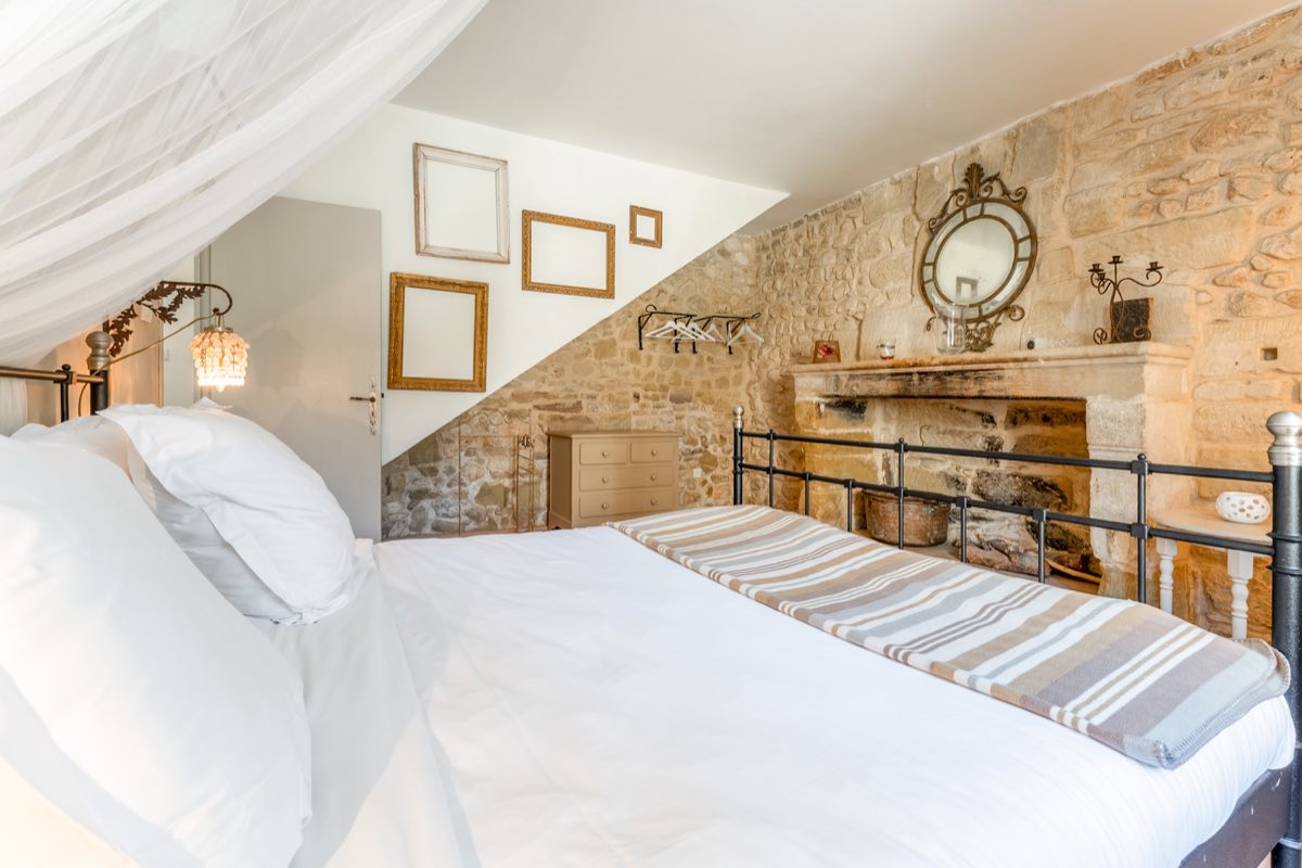 Chambre individuelle du Mas de Rey, lit en fer forgé et ancienne cheminée en pierre