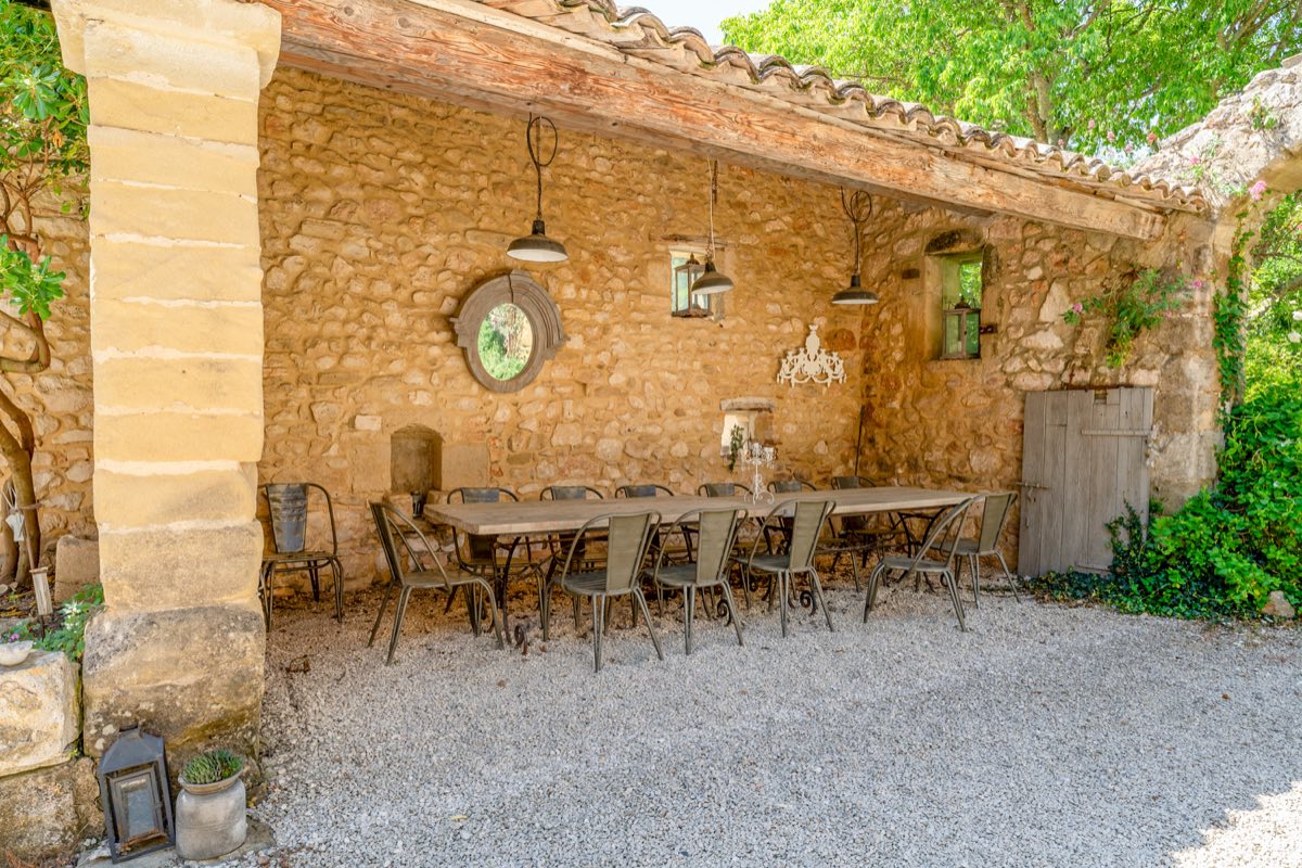 L'espace repas extérieur du Mas de Rey, grande table sous un auvent en pierre