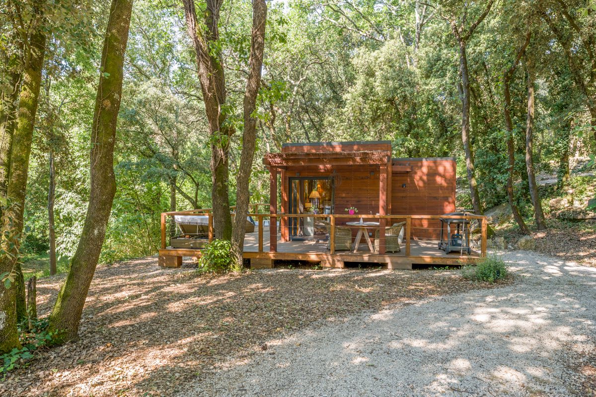 Un lodge en bois du Mas de Rey et sa terrasse, au milieu des chênes
